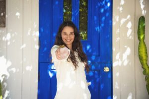 Ilona Barnhart at Four Moons Spa in Encinitas California with blue door and a rose quartz in hand